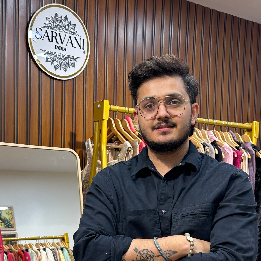 Man standing in a clothing store with 'Sarvani' branding in the background